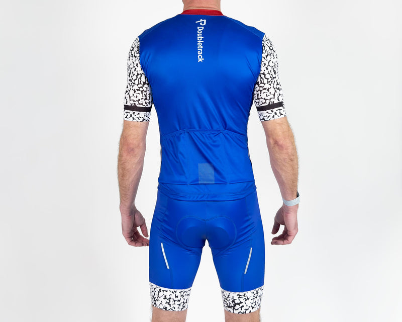 Load image into Gallery viewer, rear view athletic man wearing tight fitting spandex cycling jersey and cycling bibs
